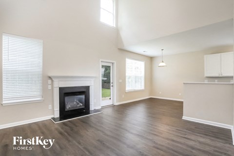 an empty living room with a fireplace and a kitchen