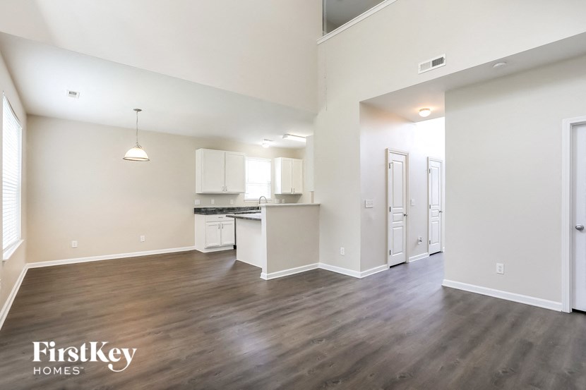 an empty living room and kitchen with wood flooring