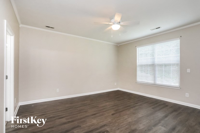 an empty living room with wood flooring and a ceiling fan