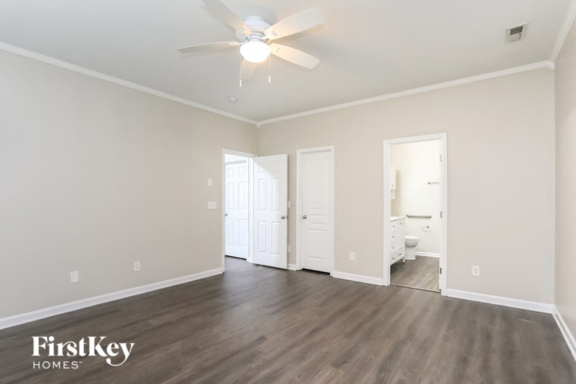 an empty living room with wood flooring and a ceiling fan