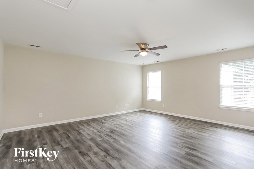 an empty living room with a ceiling fan and a window