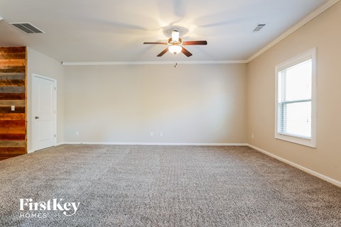 a empty living room with a ceiling fan and a window