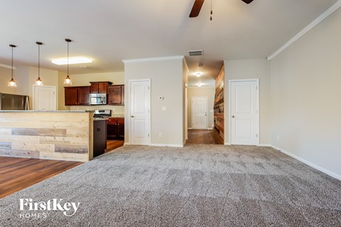 an empty living room with a kitchen and a rug