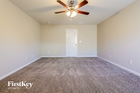 the spacious living room with ceiling fan and carpet