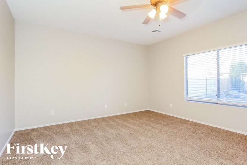 A room with a carpeted floor and a ceiling fan.
