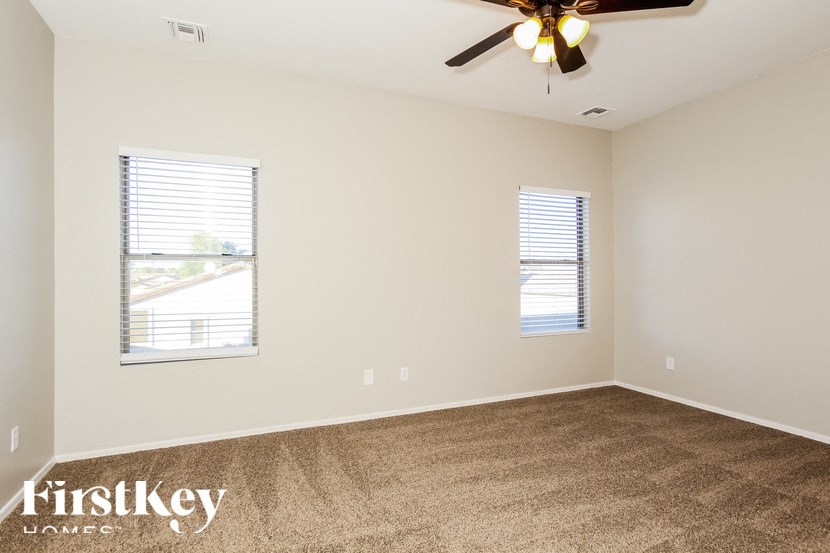 A room with a ceiling fan and two windows.
