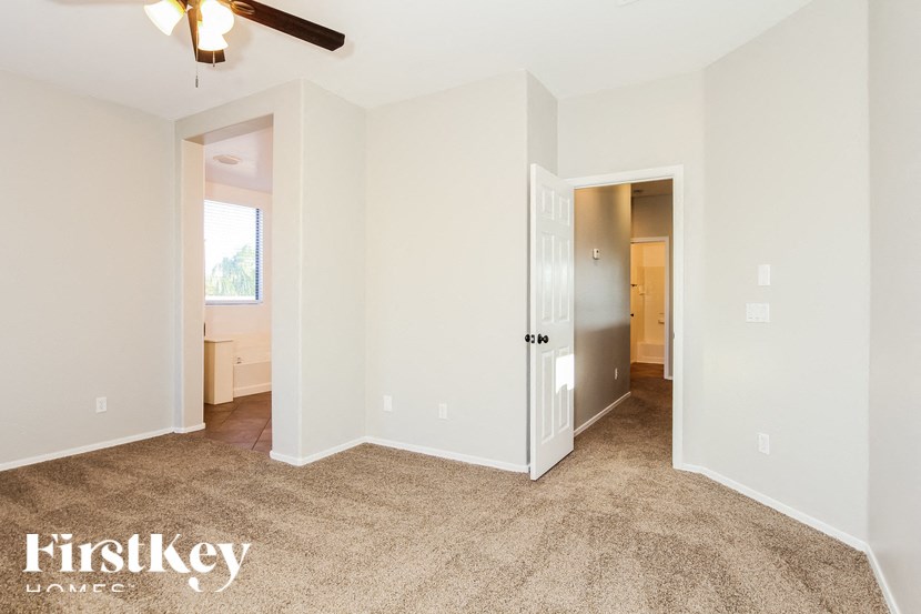 A carpeted room with a ceiling fan and two doors.