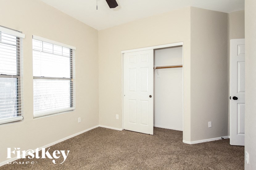 A room with a carpeted floor and a ceiling fan.