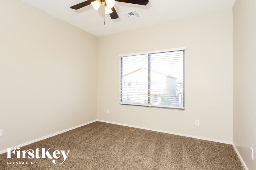A room with a ceiling fan and a window with blinds.