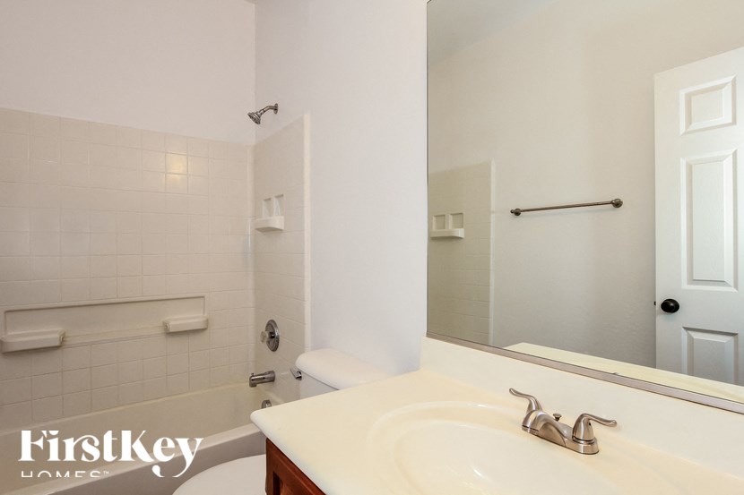 A white bathroom with a sink, mirror, and toilet.