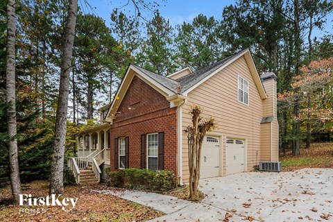the front of a brick house with a garage and a driveway