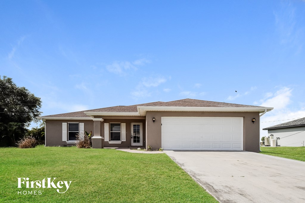 a beige house with a garage door and a lawn