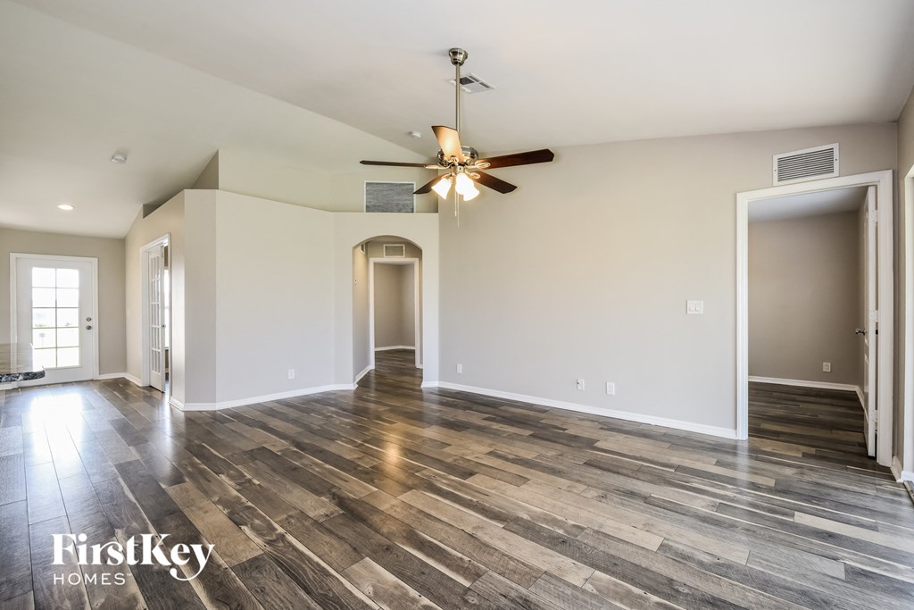 the living room and dining room of an empty house with a ceiling fan