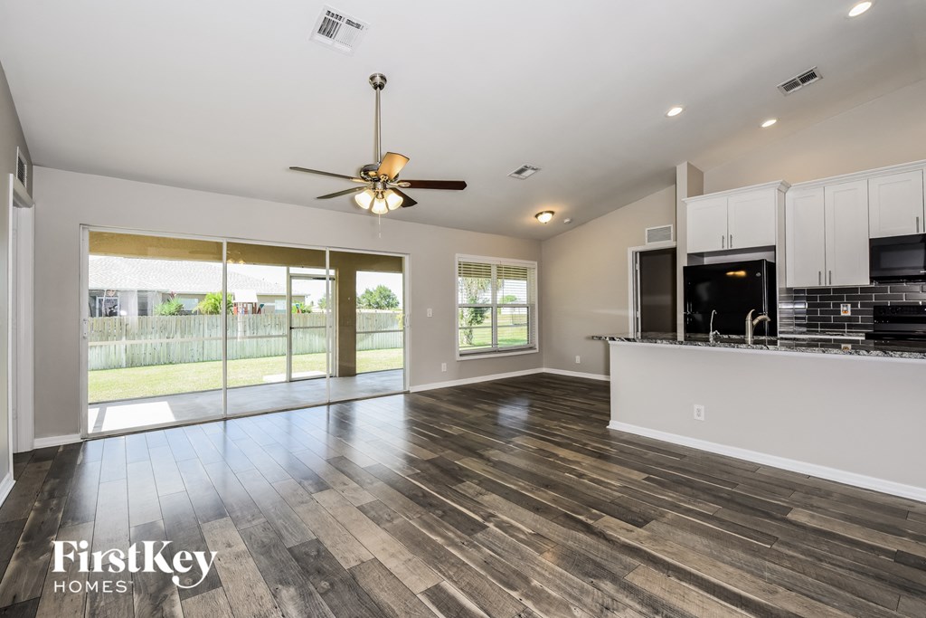 a living room with a kitchen and a ceiling fan
