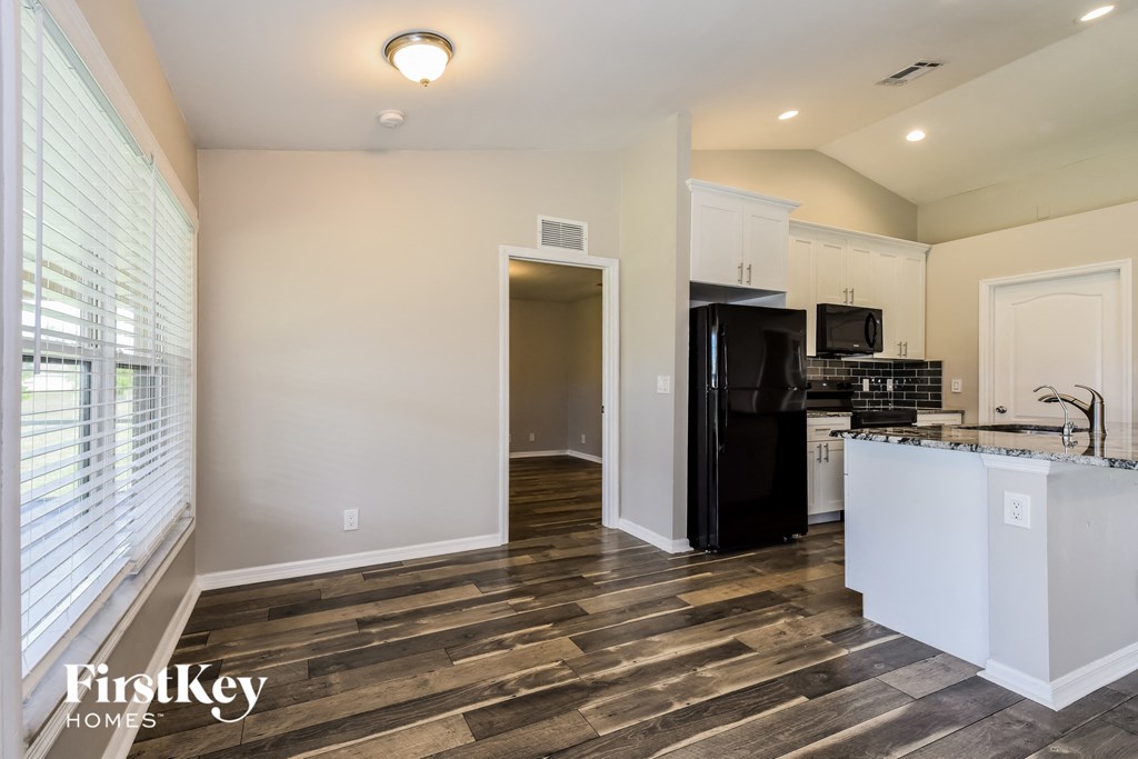 a kitchen with white cabinets and a black refrigerator