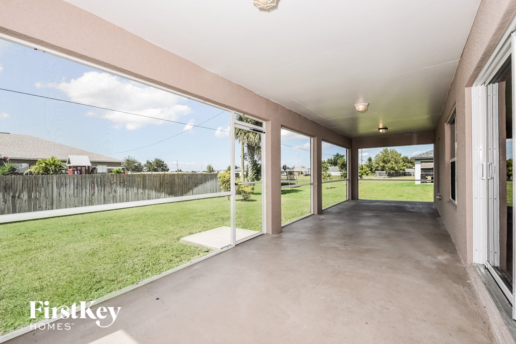 a patio with glass sliding doors and a grass field
