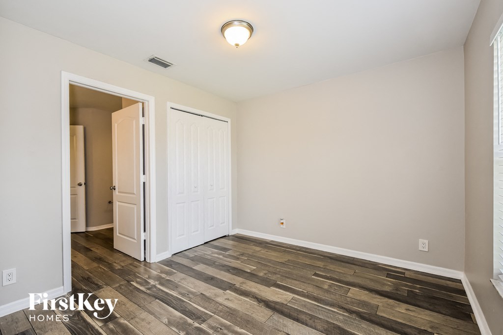 the spacious living room with wood flooring and a door to the bedroom