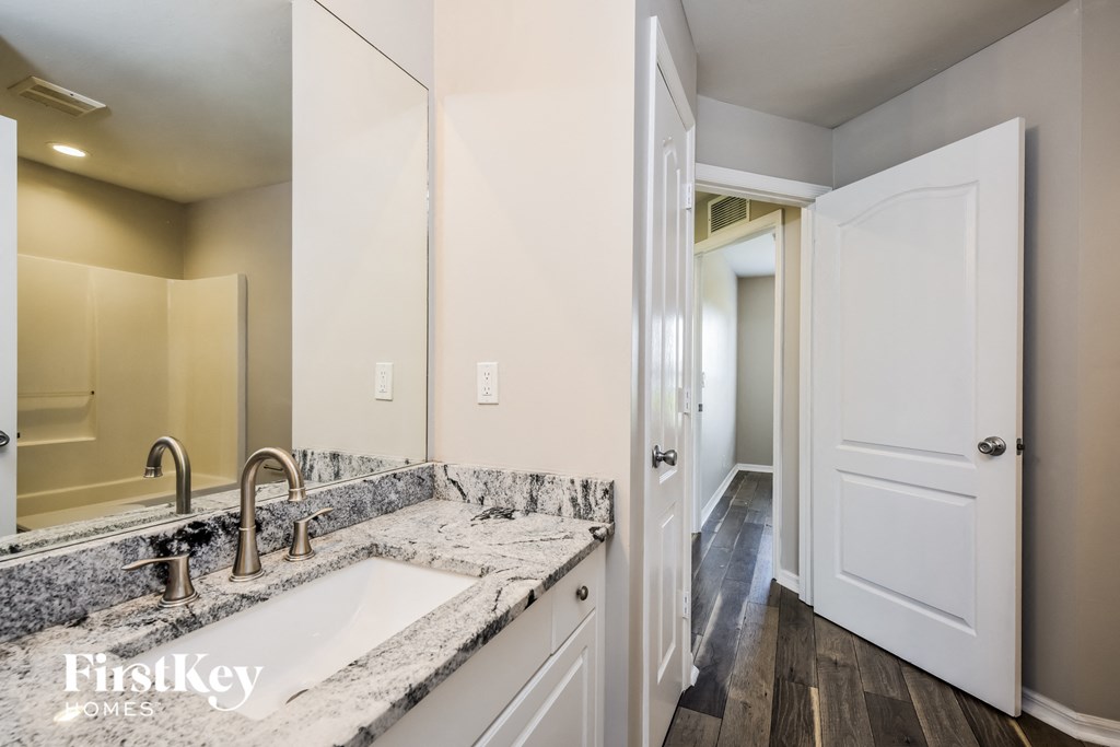 a kitchen with white cabinets and a sink and a door to a hallway