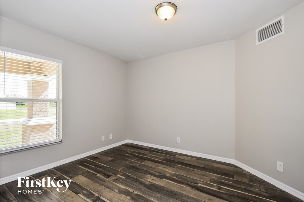 the spacious living room with wood flooring and a large window