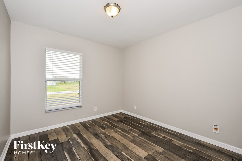 the living room of a home with wood flooring and a window