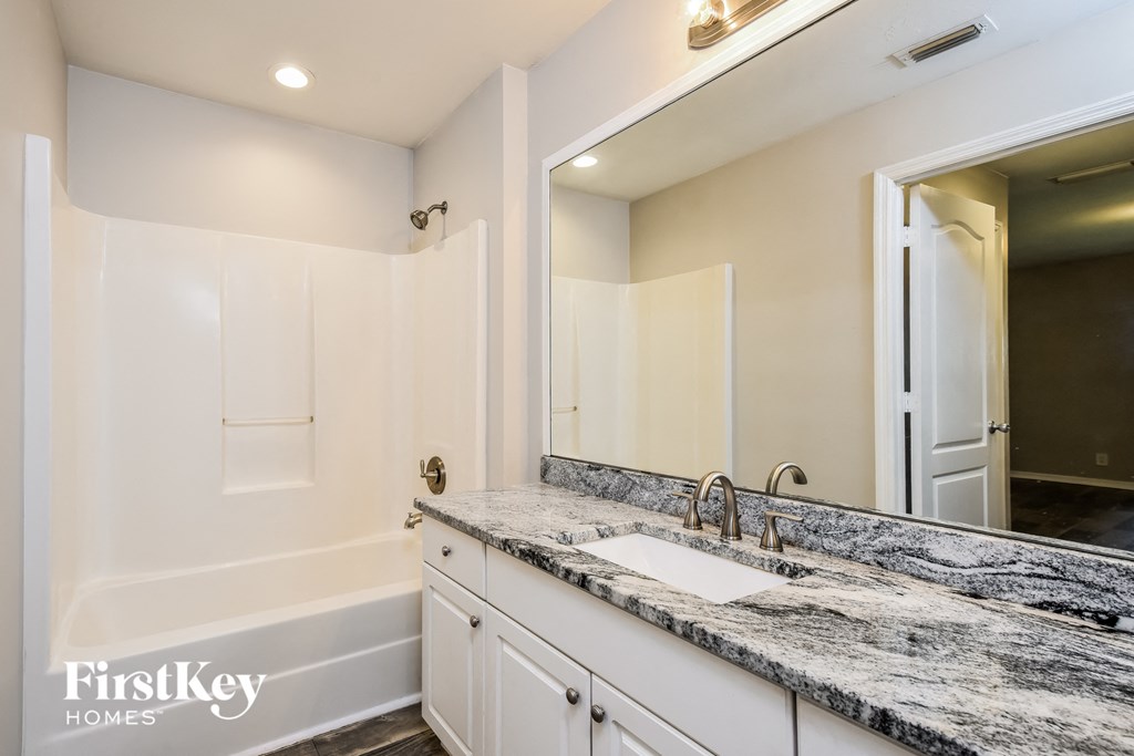 a bathroom with white cabinets and granite counter tops and a large mirror