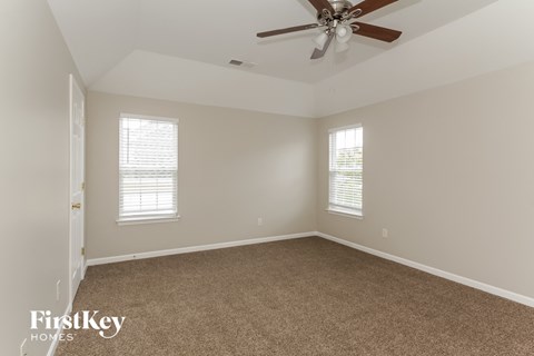 a bedroom with a ceiling fan and a carpet