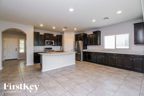 A spacious kitchen with black cabinets and a white island.
