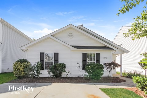 a white house with black shutters and a sidewalk in front of it