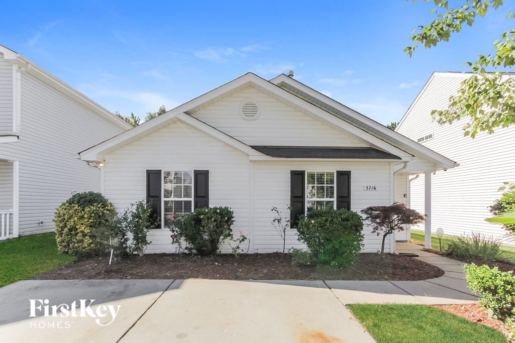 a white house with black shutters and a sidewalk in front of it