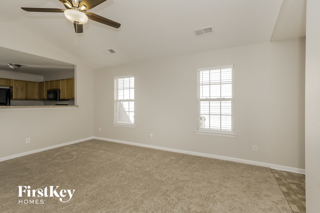 an empty living room with a ceiling fan and a window