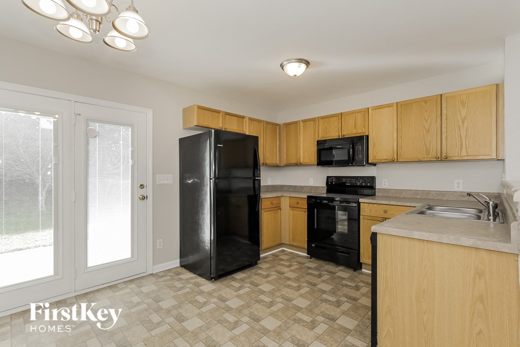 an empty kitchen with black appliances and wood cabinets