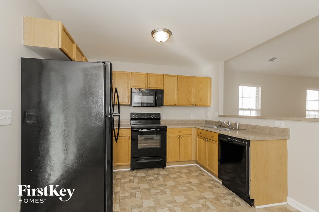 a kitchen with wood cabinets and black appliances and a refrigerator