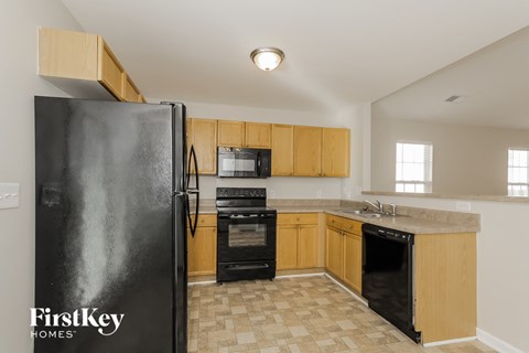a kitchen with wood cabinets and black appliances and a refrigerator