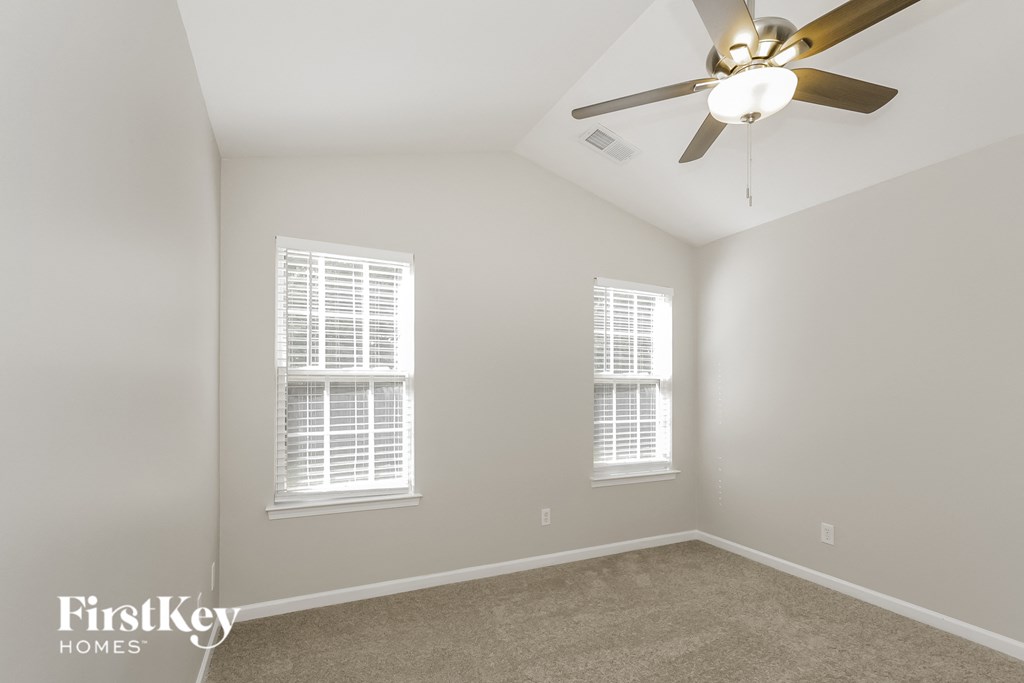 a bedroom with a ceiling fan and two windows