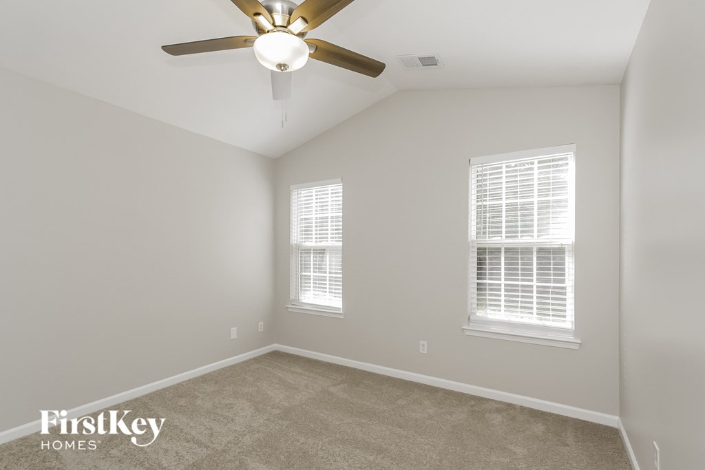 a bedroom with a ceiling fan and two windows