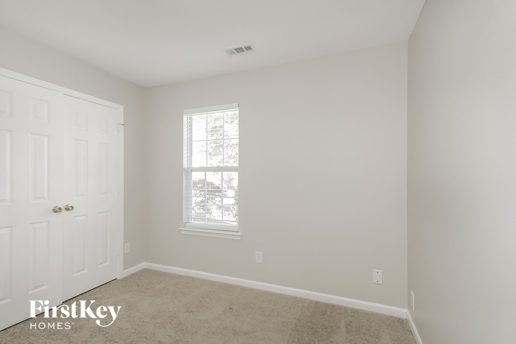 a bedroom with white walls and a window and a white door