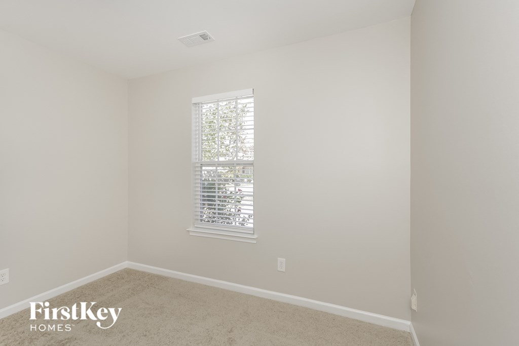 a bedroom with white walls and a window