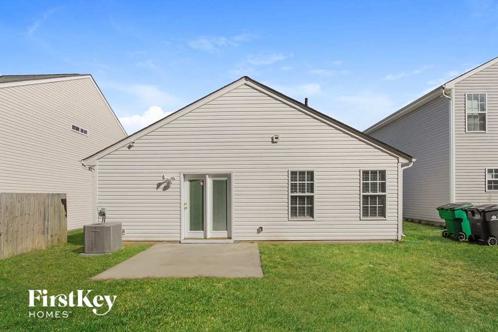 the exterior of a white house with a grassy yard and a driveway