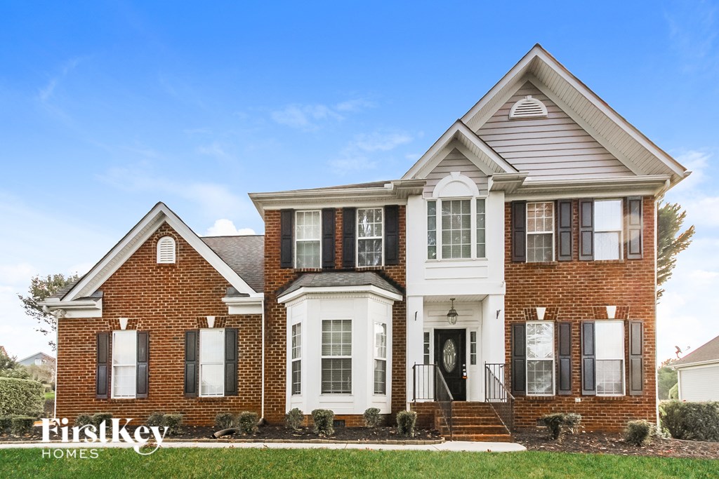 a large brick house with white columns and a black door