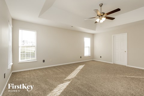 a spacious living room with carpet and a ceiling fan