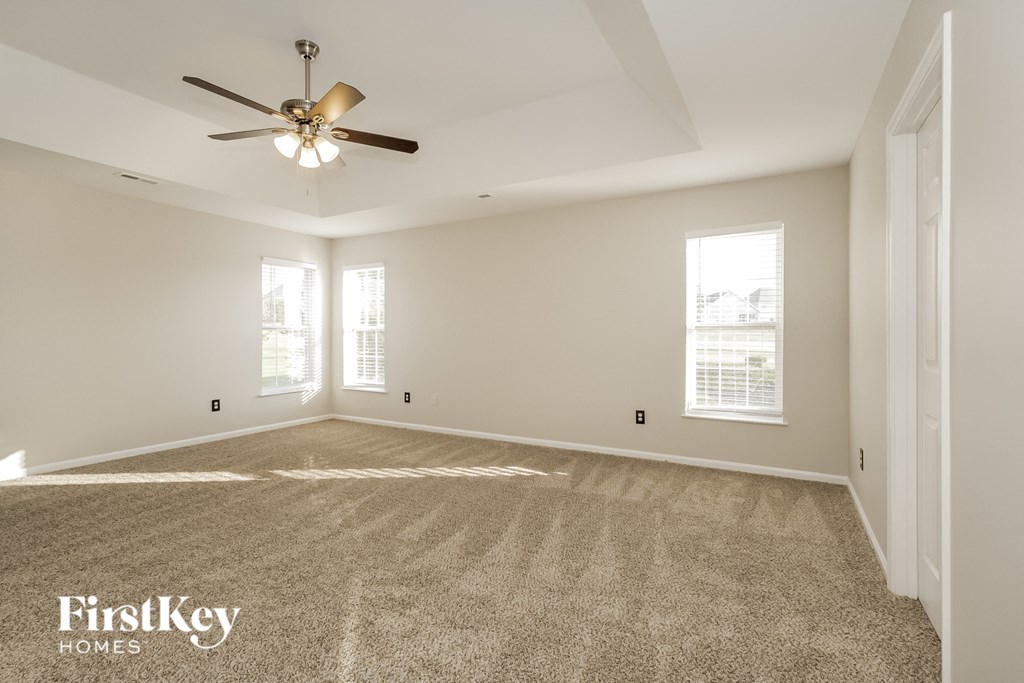 a spacious living room with carpet and a ceiling fan