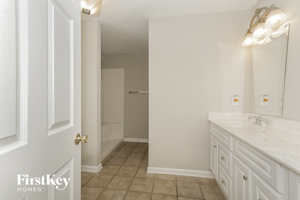 a bathroom with white cabinets and a sink and a mirror