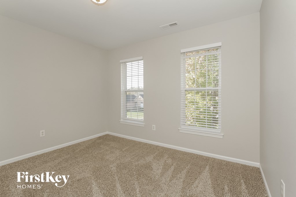 a bedroom with a carpeted floor and two windows