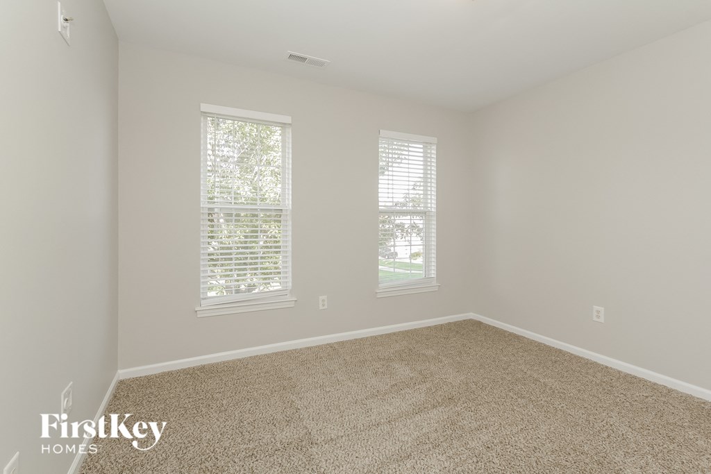 a room with carpet and two windows
