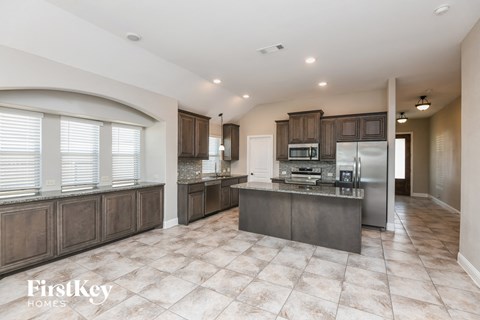 A kitchen with a tile floor and a large island in the middle.
