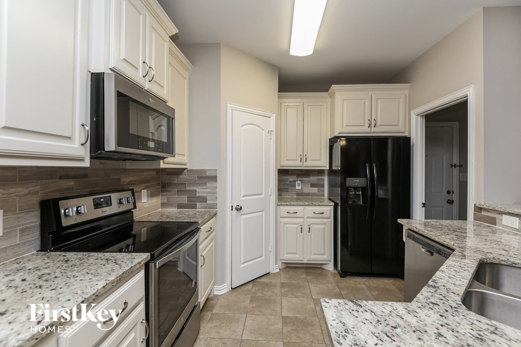 a kitchen with white cabinets and black appliances