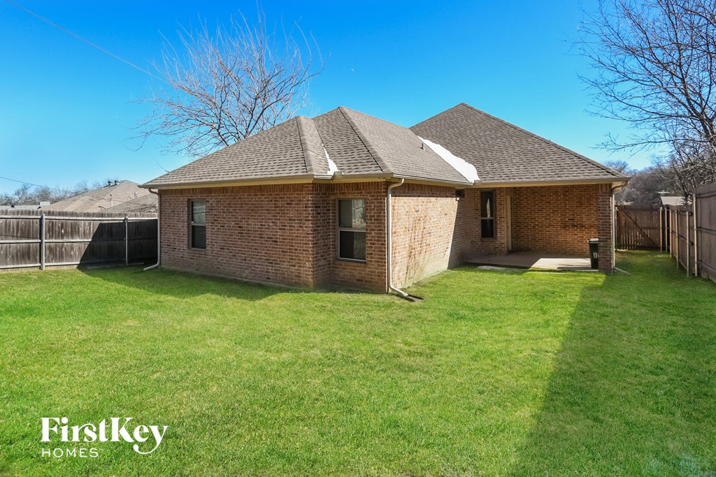 a small brick house with a backyard and a fence