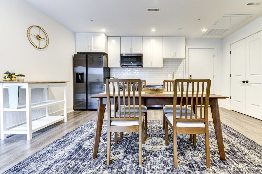 a dining room with a table and chairs and a kitchen with a refrigerator