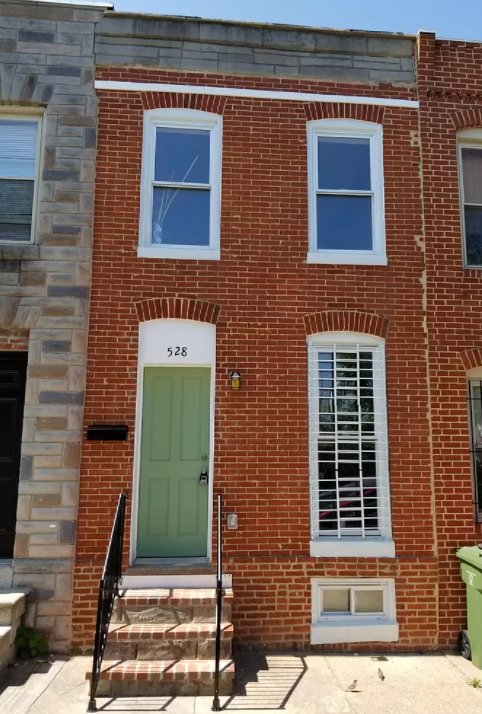 the front of a brick house with a green door