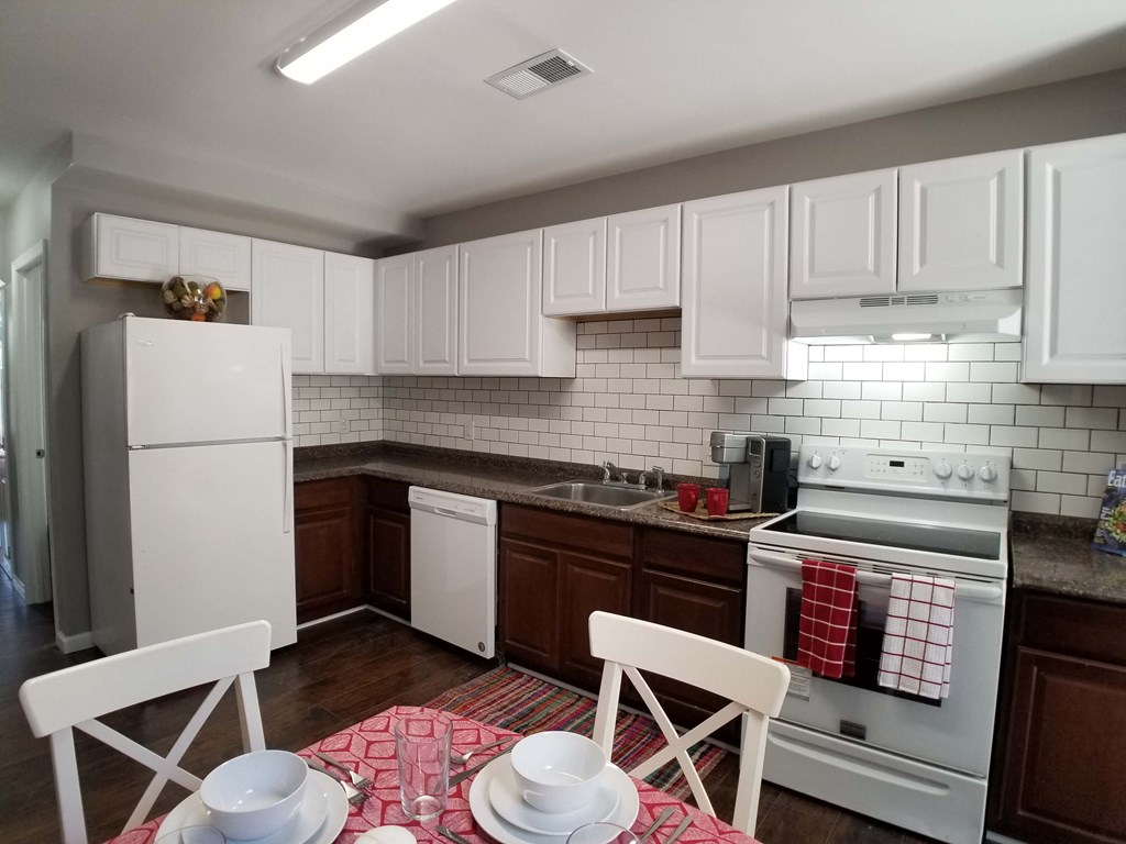 a kitchen with white appliances and a table and chairs